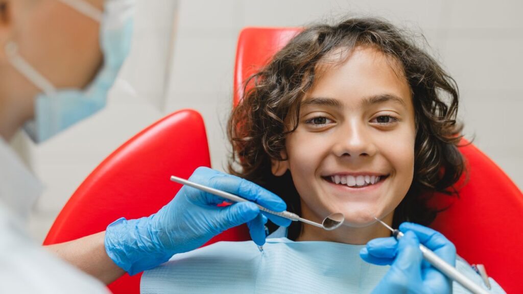 child smiles at dentist with dental tools