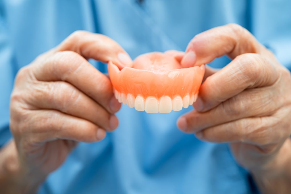 dentures being held by person wearing blue